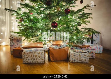 Beautiful Christmas gifts under Christmas tree on the floor in the living room. Celebrating winter holidays at home. Stock Photo