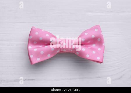 Stylish pink bow tie with polka dot pattern on white wooden table, top view Stock Photo