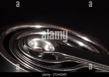 Picture of measuring teaspoons, concentrical, of various quantities, using metric system and milliliters, isolated on black background. Stock Photo