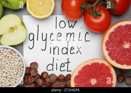 Paper with words Low Glycemic Index Diet and food on grey table, flat lay Stock Photo