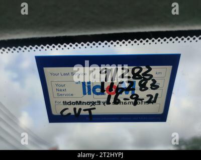 Malaysia, 15 April 2022: Next service sticker for CVT oil is pasted on the inside of the car windshield. Stock Photo