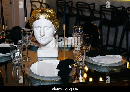 Elegant table setting in luxury restaurant.  White marble bust of woman Venus on the table. Luxury interior. Stock Photo