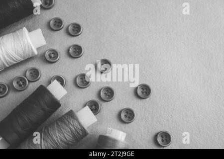 A beautiful black and white texture with many round buttons for sewing, needlework and coils of yarn. Copy space. Flat lay. the background. Stock Photo