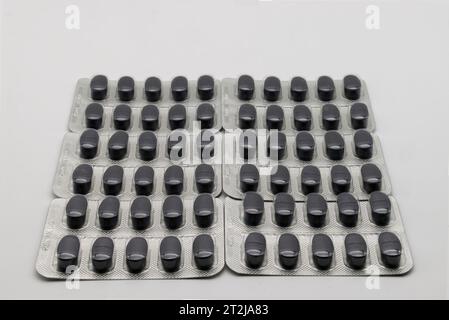 Blister pack of medical black capsules on white background. Stock Photo
