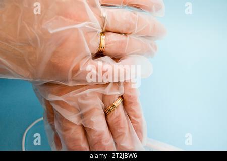 Gold wedding rings on hands in protective medical rubber disposable gloves for protection against dangerous deadly diseases of microbes and viruses by Stock Photo