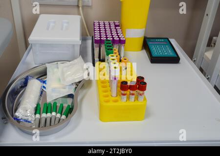 laboratory diagnostics. test tubes with multi-colored caps are in the holder. next to it is a medical vessel with needles and transfer material, tourn Stock Photo