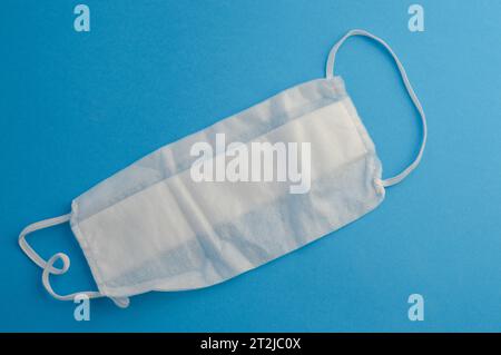 white disposable mask on a blue matte background. a gauze mask to protect the respiratory system from infections. personal respiratory protection mask Stock Photo