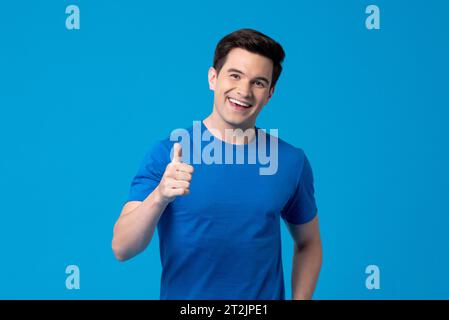 Smiling handsome young Caucasian man giving thumbs up in light blue isolated background Stock Photo