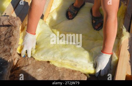 Attic roof construction with fiberglass insulation for energy saving. Roofing contractor laying mineral wool insulation during house roof attic insula Stock Photo