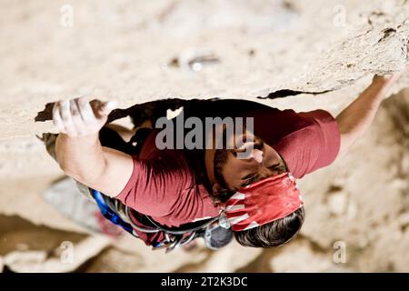 A rock climber strains while reaching for his next hold. Stock Photo