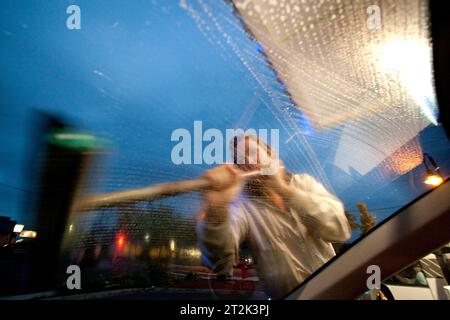 A woman washes a dirty windshield at a gas station while on a road trip through Oregon. Stock Photo