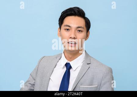 Portrait of young handsome Asian man in formal business suit on isolated light blue studio background Stock Photo