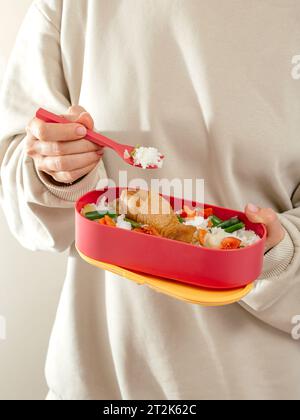 a girl eats food from a lunch box in the office. lunch box to th Stock Photo