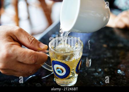 Close-up of hand pouring tea into glass cup Stock Photo