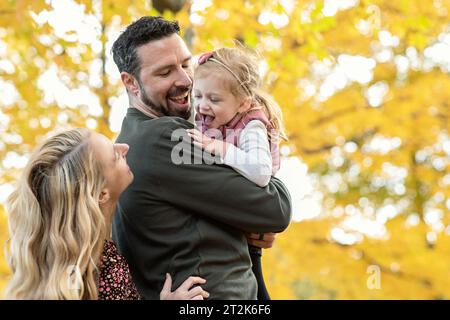 Family of three playing peek a boo with daughter Stock Photo