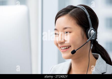 Smiling beautiful Asian woman customer service operator wearing headset working in call center office Stock Photo