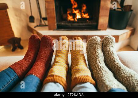 Legs view of happy family wearing warm socks in front of fireplace - Winter, love and cozy concept - Focus on center and left socks Stock Photo