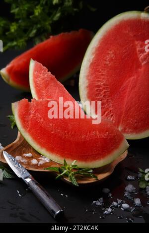 Close-up of a cut round ripe watermelon on a black background. Stock Photo