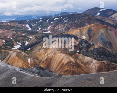 Hikers walking on the edge of a ridge in a colored landscape in Iceland Stock Photo