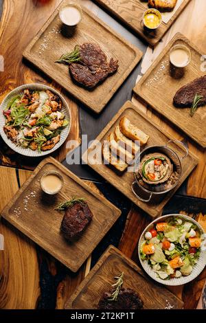 Tasty dishes in restaurant with beef steak, salad and barbecue chicken wings. Food menu concept Stock Photo