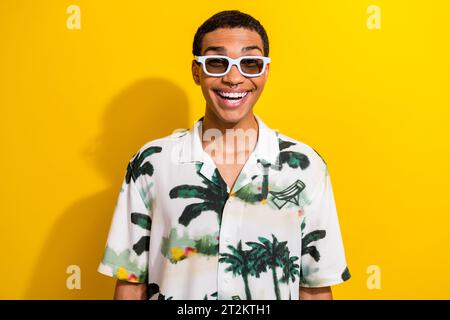 Photo of positive optimistic guy wear stylish clothes summer glasses enjoying weekend isolated on vivid yellow color background Stock Photo