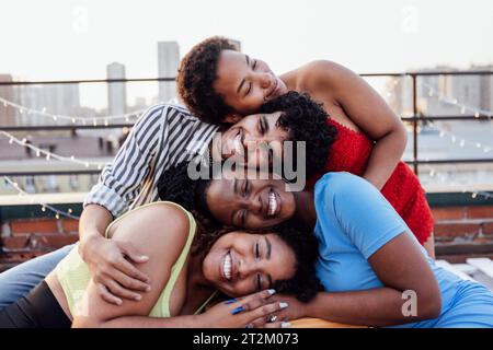 Four multiethnic friends put their heads on top of each other. Young people of mixed race against the backdrop of a big city. Cute African girls and a Stock Photo