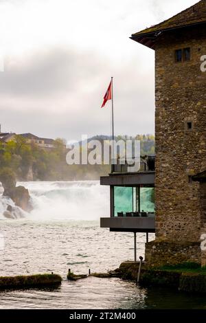 Rhine Falls and Swiss Flag with a Building at Neuhausen, Schaffhausen, Switzerland Stock Photo