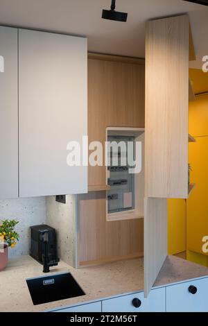 Custom kitchen cabinet with hidden circuit breaker box in small urban apartment Stock Photo
