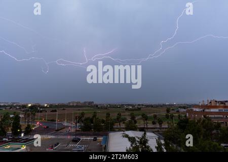 Stormy sky with several huge lightnings bolts on the outskirts of a city over agricultural fields. Weather concept Stock Photo