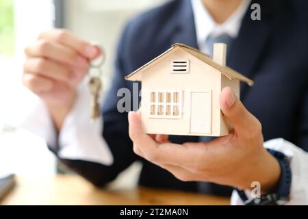 Hand of man holding model house. Mortgage, home loan, real estate insurance and banking concept.. Stock Photo