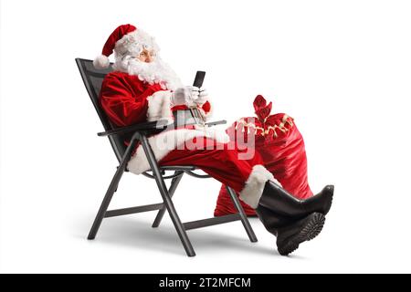 Santa claus sitting in a foldable chair and using a smartphone isolated on white background Stock Photo
