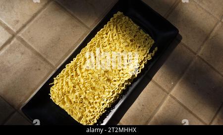 yellow curly noodles on a black plate uncooked Stock Photo