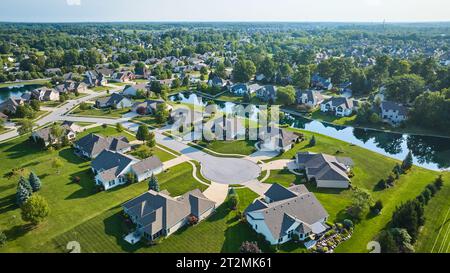 Aerial over culdesac with suburban houses in neighborhood with manmade river between homes Stock Photo