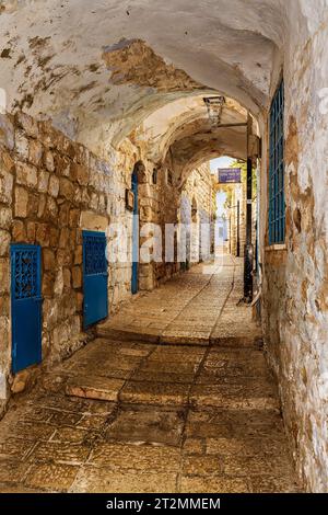 A narrow cobblestone street or alley in the Jewish quarter of Israel's highest elevation city, Tzafet (Safed). Sign Translation: Rabbi Moshe Elsheich Stock Photo