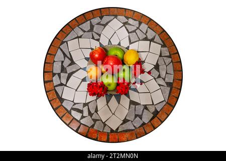 Bowl of fruit with red and green apples, lemons, and oranges on a mosaic tile table. Top view. Isolated on white background. Stock Photo