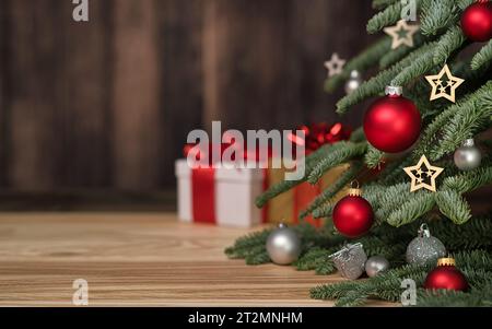 Christmas tree with ornaments, gift boxes and dark wooden wall as copy-space in the background Stock Photo