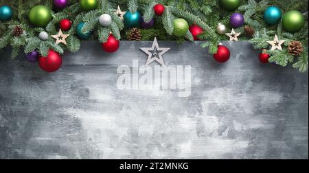 Modern Christmas background with an arch-shaped border composed of fir branches, colorful baubles and stars, on hand-made gray textured surface as cop Stock Photo