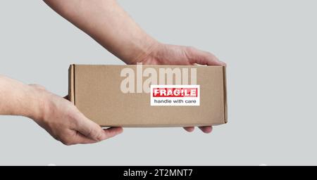 A rectangular cardboard box. Monochrome light background. An adhesive warning labels for packaging. Red, white, black, beige Stock Photo