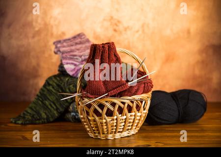 Colored yarn, knitting needles and other items for hand knitting on a dark wooden table. Stock Photo