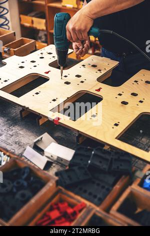 Worker's hands on a workbench with different tools using a screwdriver Stock Photo