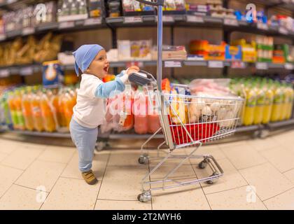 October 18 2023-Bucharest-Romania-Adorable and happy little boy who just learned to walk filled the children's shopping basket with all kinds of produ Stock Photo