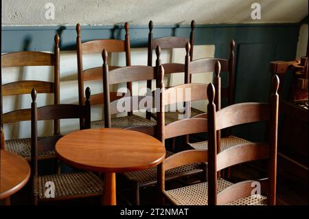 A group of Shaker chairs bearing the signature Harvard spindles gathered in a small room in the Shaker House at the Fruitlands Museum – Harvard, Massa Stock Photo