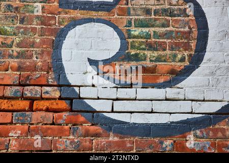 Redish brown brick wall with white swirl of paint surrounded by dark blue paint background asset Stock Photo