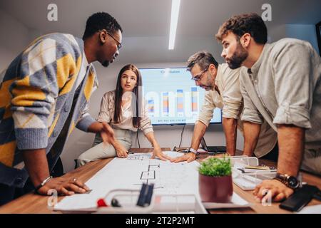 International Team Collaborating on Architectural Blueprint in a Multiracial Board Room Stock Photo