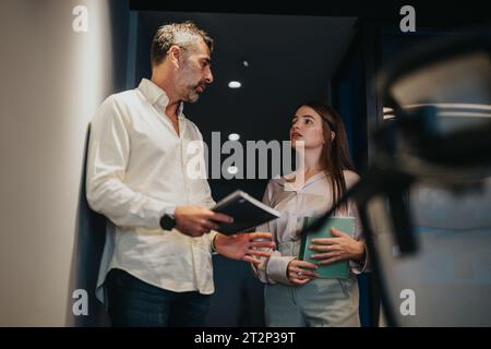 Business partners discussing efficiency and ideas in a corporate workplace, collaborating for better productivity and growth. Stock Photo