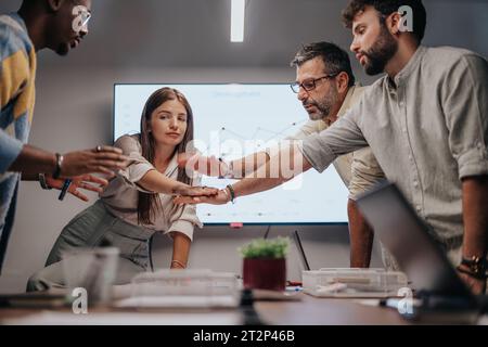 Multiracial team discusses architectural plans, graphs, and blueprints. Successful team putting hands together. Stock Photo