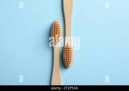 Two bamboo toothbrushes on light blue background, flat lay Stock Photo