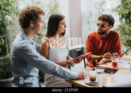 Architects, engineers, and executives discuss blueprints at a coffee bar, collaborating on a new urban planning project with successful teamwork. Stock Photo