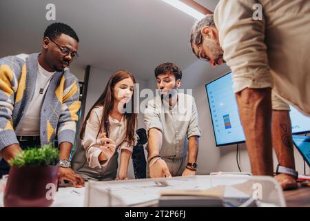 Multiracial Team of Architects Collaborating on Project Blueprint in Board Room Stock Photo