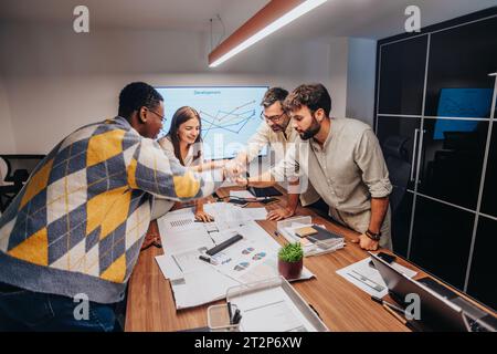 Innovative Multiracial Team Discussing Architectural Blueprint in Collaborative Business Meeting Stock Photo